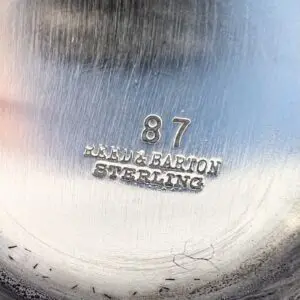 Silver object with engraved text and numbers.