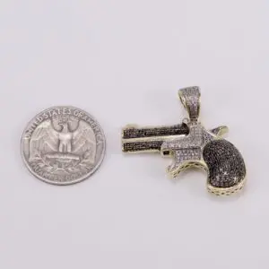 Gun-shaped pendant next to a quarter.