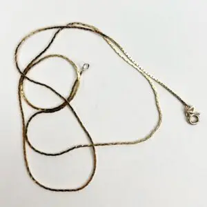 Gold chain necklace with clasp on white.