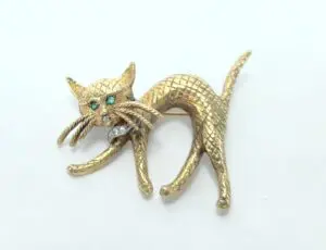 Golden cat brooch with emerald eyes.