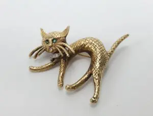 Gold cat brooch with green gemstone eyes.