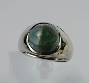 Silver ring with green gemstone on display.