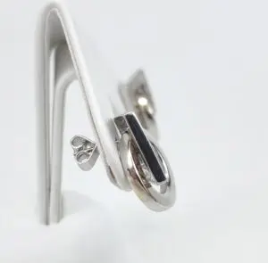 Silver earrings on a white display stand.