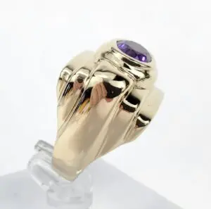 Gold ring with purple gemstone on stand.