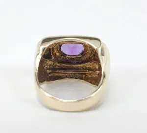 Gold ring with purple gemstone inside.