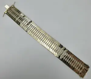 Wide gold bracelet with intricate design.