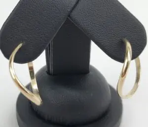 Gold hoop earrings on black display stand.