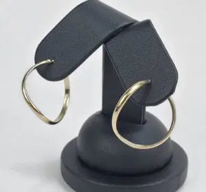 Gold hoop earrings on black display stand.