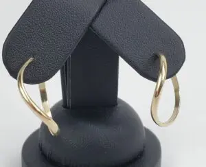 Gold hoop earrings on black stand.