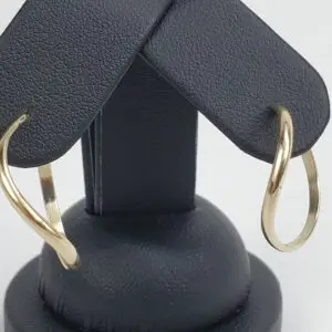 Gold hoop earrings on black stand.