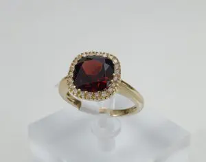 Gold ring with red gemstone and diamonds.