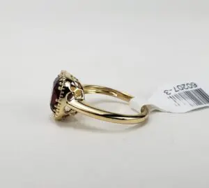 Gold ring with red gemstone and tag.