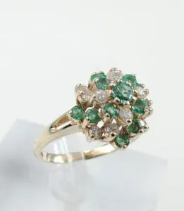 Gold ring with emerald and diamond cluster.