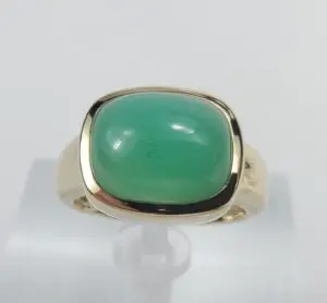 Gold ring with green gemstone on display.