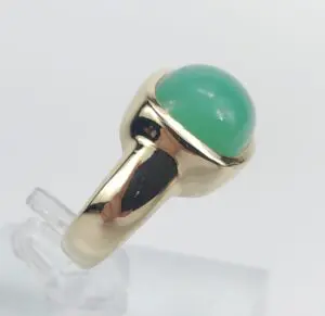 Gold ring with green gemstone on display.