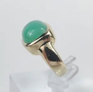 Gold ring with green gemstone on display.
