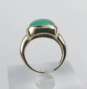 Gold ring with green gemstone on display.