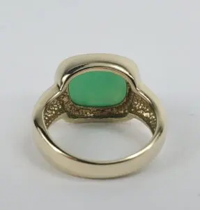Gold ring with green gemstone, rear view.