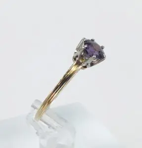 Gold ring with purple gemstone on display.