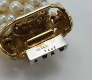 Gold clasp with pearls and engraved numbers.