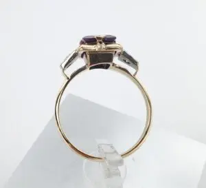 Gold ring with purple gemstone on display.