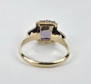 Gold ring with purple gemstone, side view.