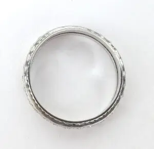 Silver ring with textured design on white background.