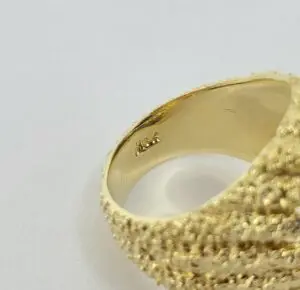 Textured gold ring on white background.