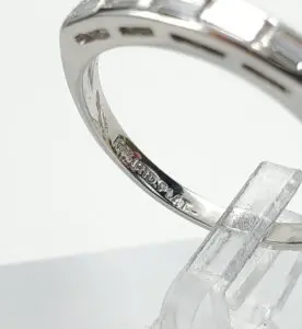 Silver ring with engraved markings on stand.
