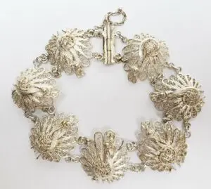 Ornate silver bracelet with intricate peacock designs.