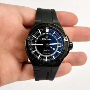 Black wristwatch with blue dial in hand.