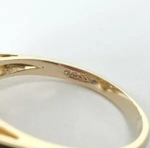 Gold ring with engraved hallmark inside band.