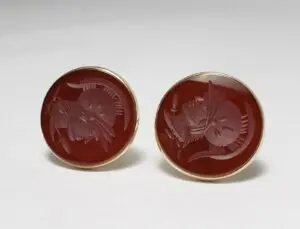 Red engraved cameo cufflinks on white background.