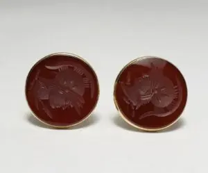 Red engraved circular cufflinks on display.