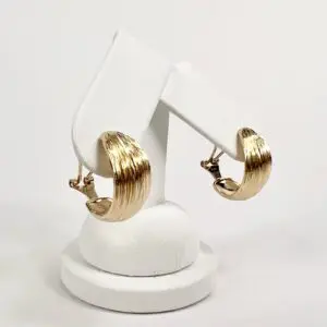 Gold hoop earrings on white display stand.
