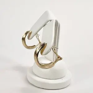 Gold hoop earrings on white stand.