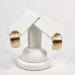 Gold textured hoop earrings on display stand.