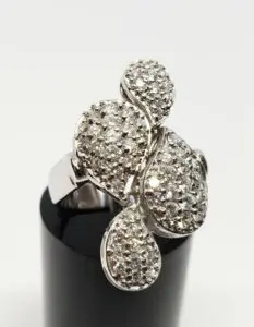 Diamond-studded silver ring on black stand.