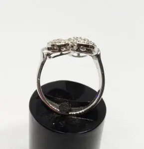Silver ring with diamond accents on stand.