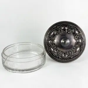 Glass container with ornate metal lid.