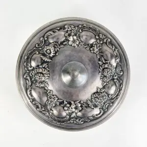 Ornate silver lid with floral decoration.