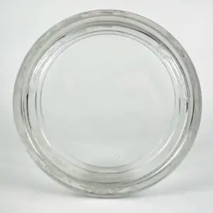 Clear glass jar lid on white background.