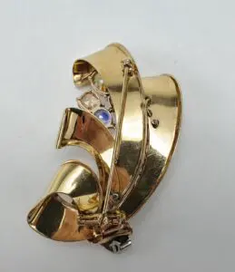 Gold brooch with intricate, curved design.