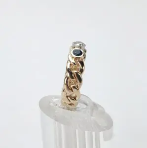 Gold chain ring with gemstones on display.