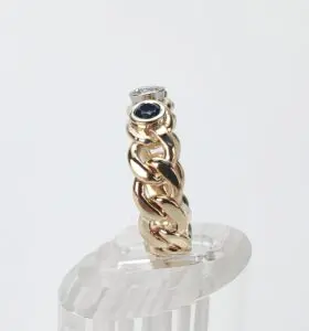 Gold braided ring with gemstones displayed.