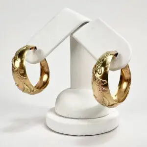 Gold hoop earrings on white display stand.