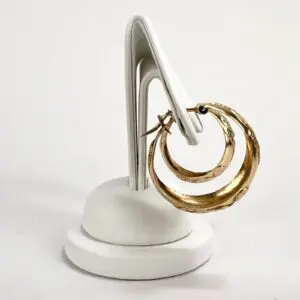 Gold hoop earrings on white display stand.