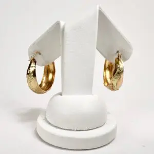 Gold hoop earrings on white display stand.
