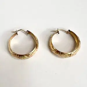 Gold hoop earrings with engraved floral design.