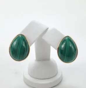 Green teardrop earrings on white stand.